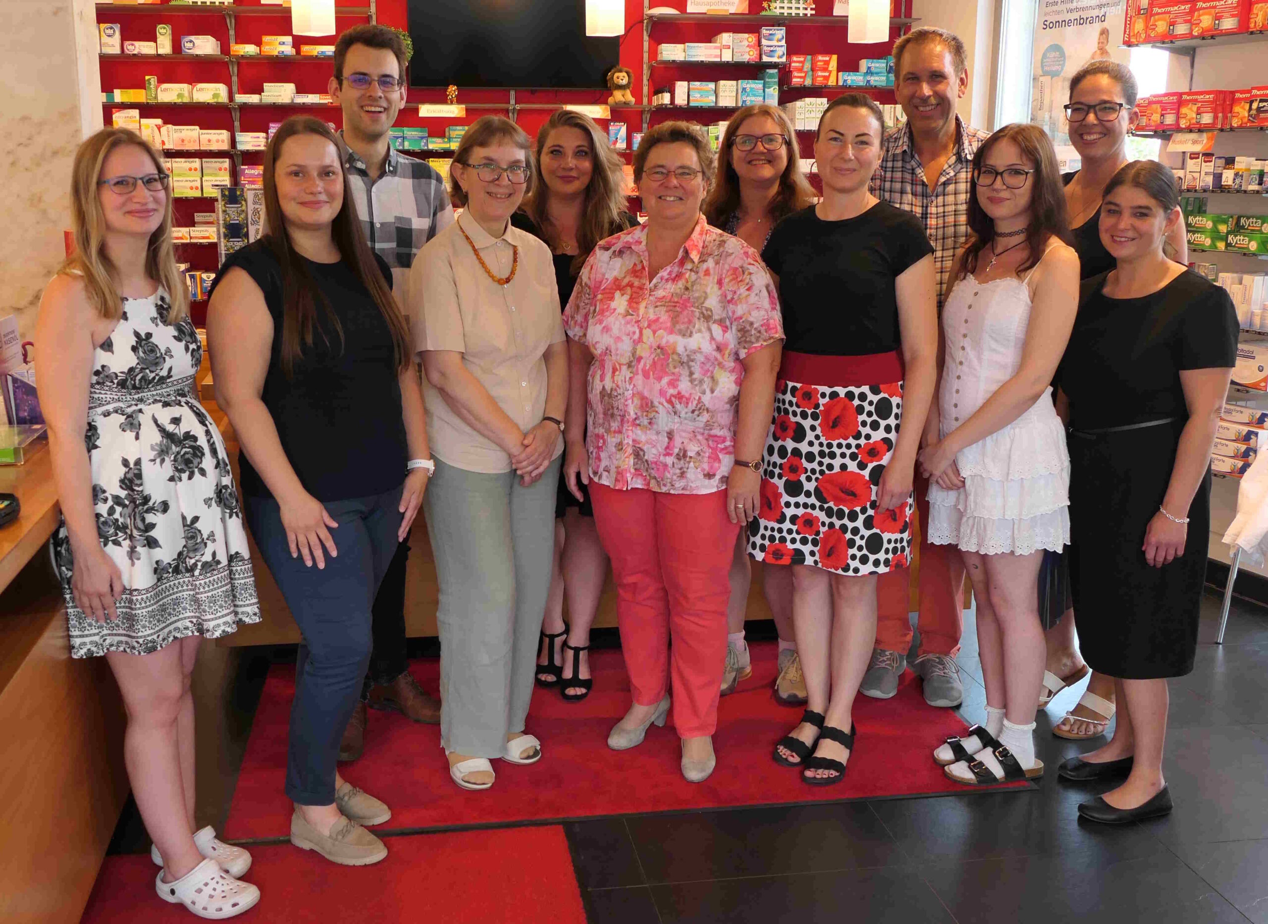Die Mitarbeiter der Apotheke Ebenfurth stehen im Verkaufsraum in Privatkleidung und freuen sich den Kunden der Apotheke Ebenfurth zu helfen.